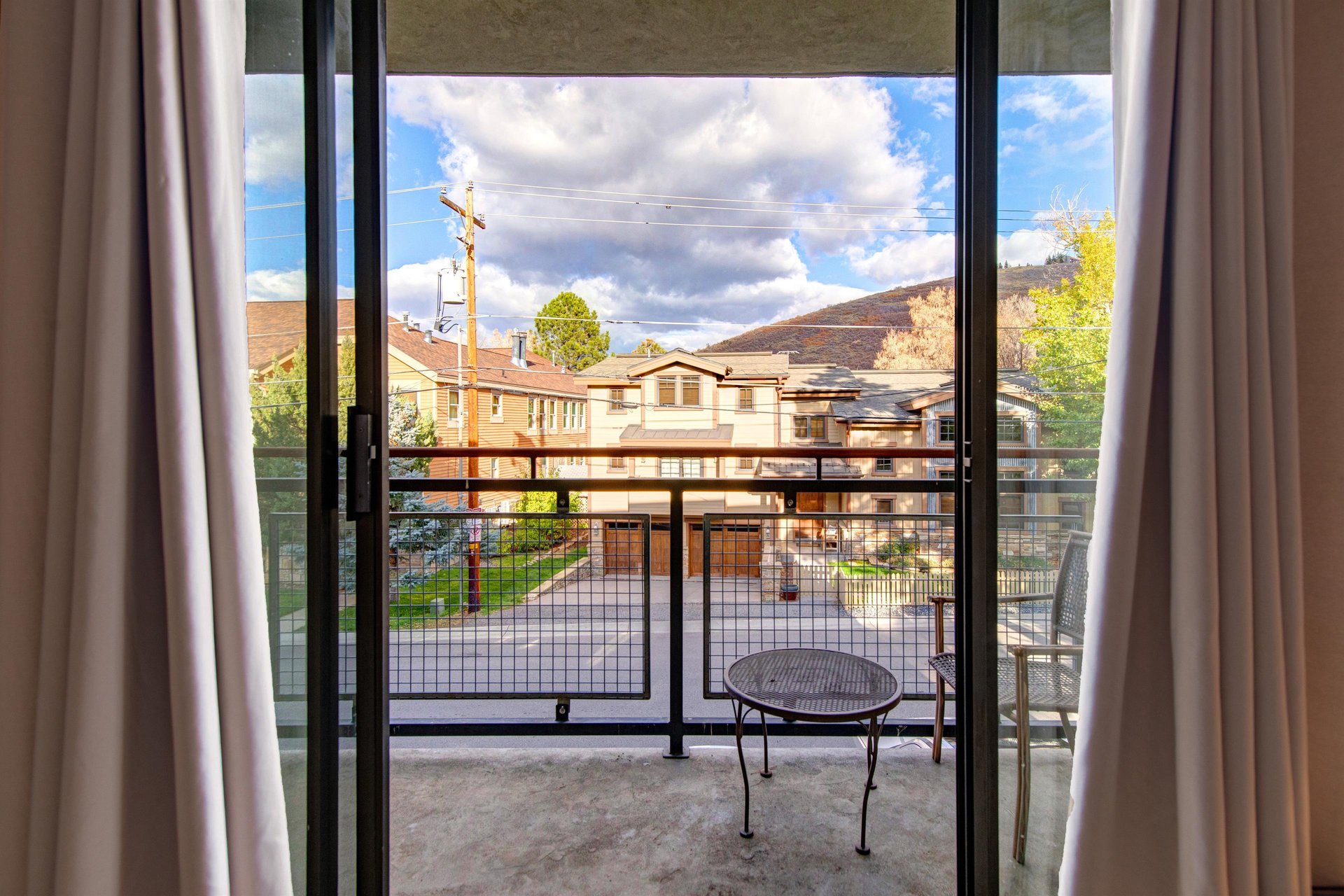 Private balcony with outdoor seating and views of the surrounding neighborhood and mountains.