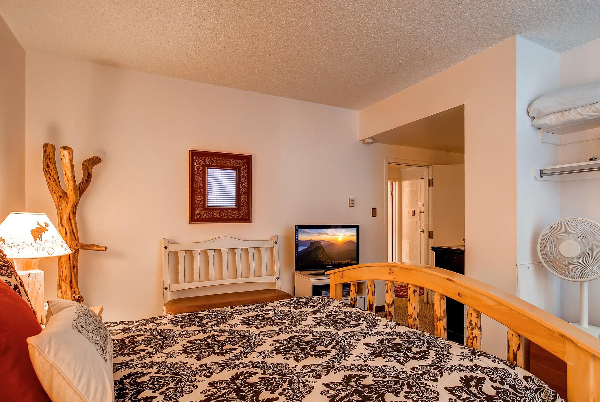 The main suite with a queen bed, TV and a bench.