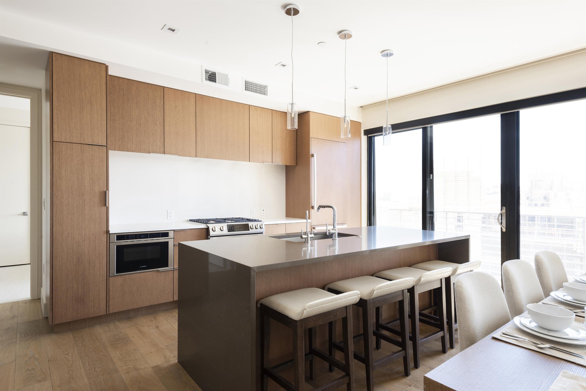 Kitchen island with dune color quartz countertops and seating for 4 in leather and wooden barstools.