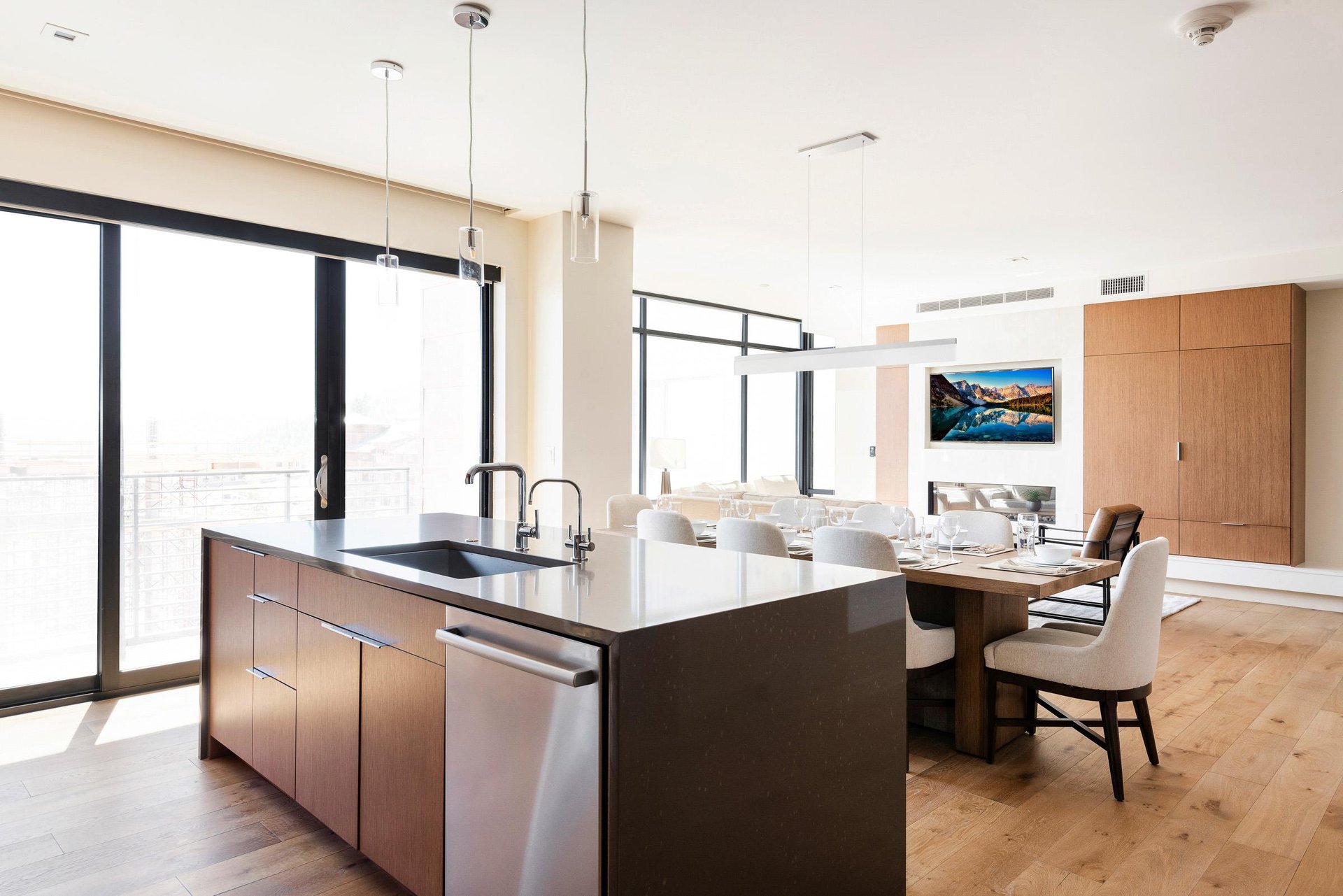 Kitchen island with quartz countertops looking toward the dining room and living room, stunning window walls and sliding glass door to access private patio.