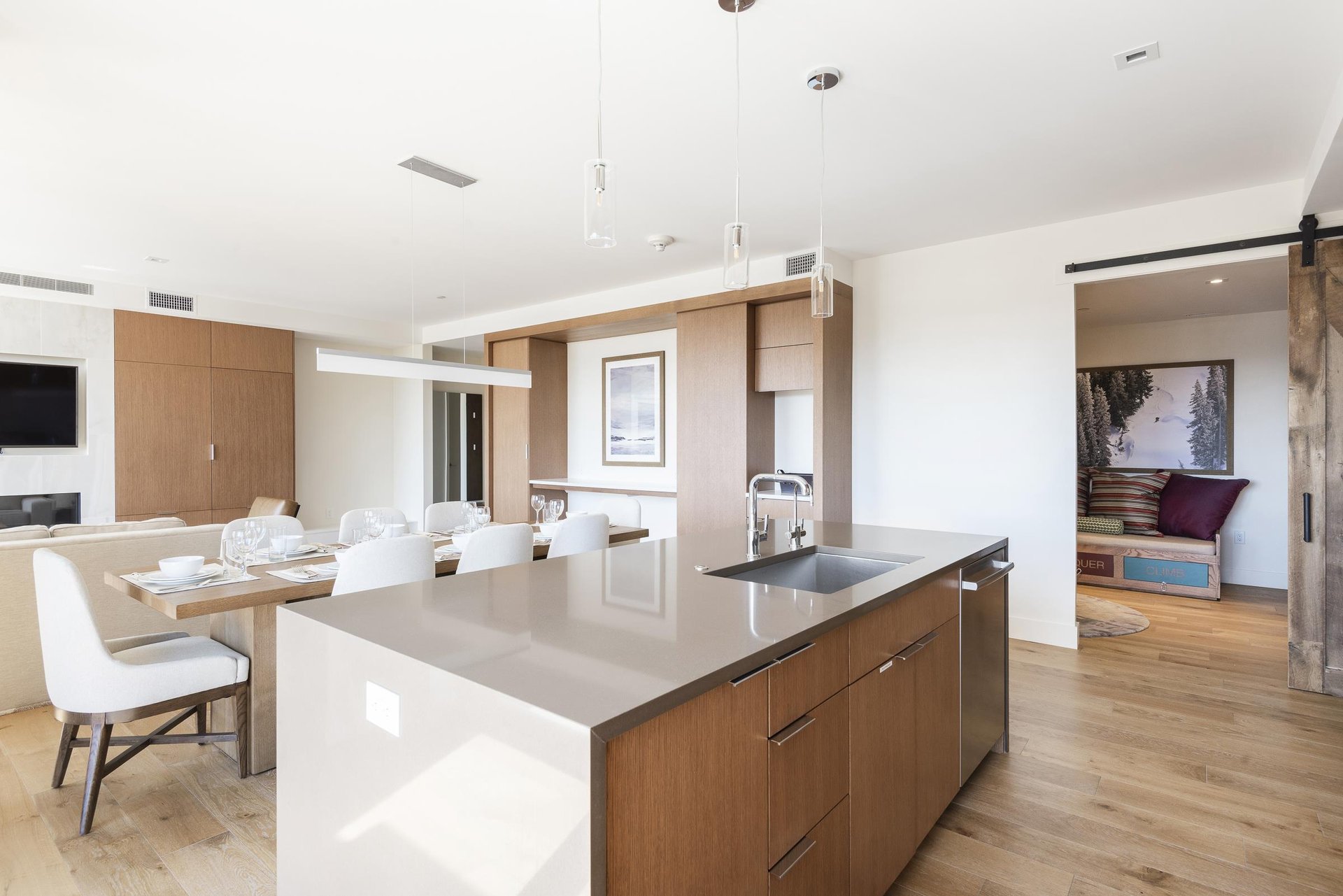 Kitchen island with pendant drop chandelier lights with view into kids bunk room with barn sliding door, dining room in the background.