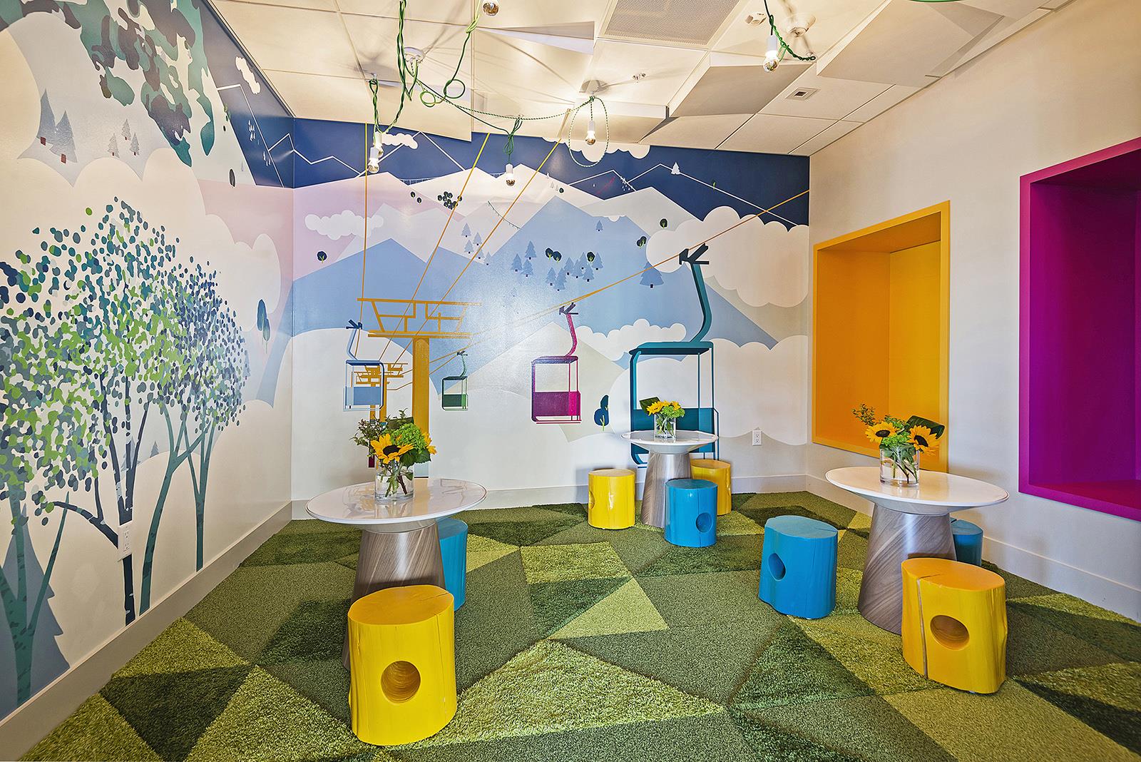 Kids lounge with bright colorful carpeting and artistic walls.