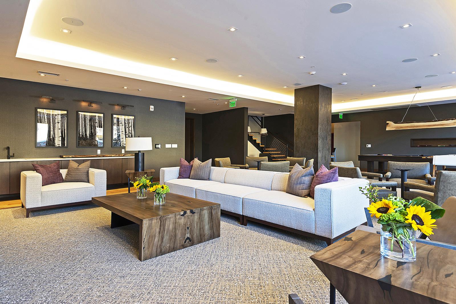 Lift club room with extra long white couch, wooden coffee table, various seating arrangements.