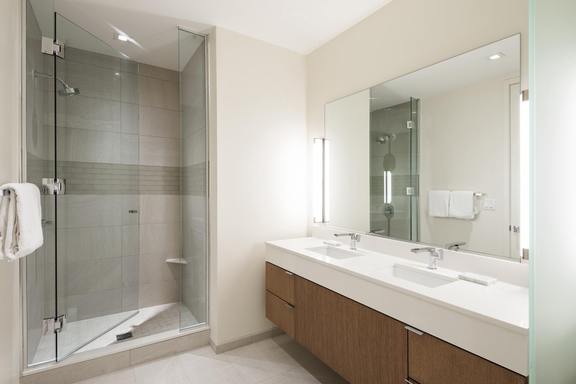 Ensuite guest bathroom, tiled shower with glass door and dual vanity.