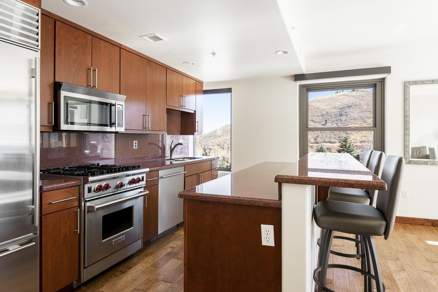 Red granite countertops in the kitchen with stainless steel appliances and chefs gas range.