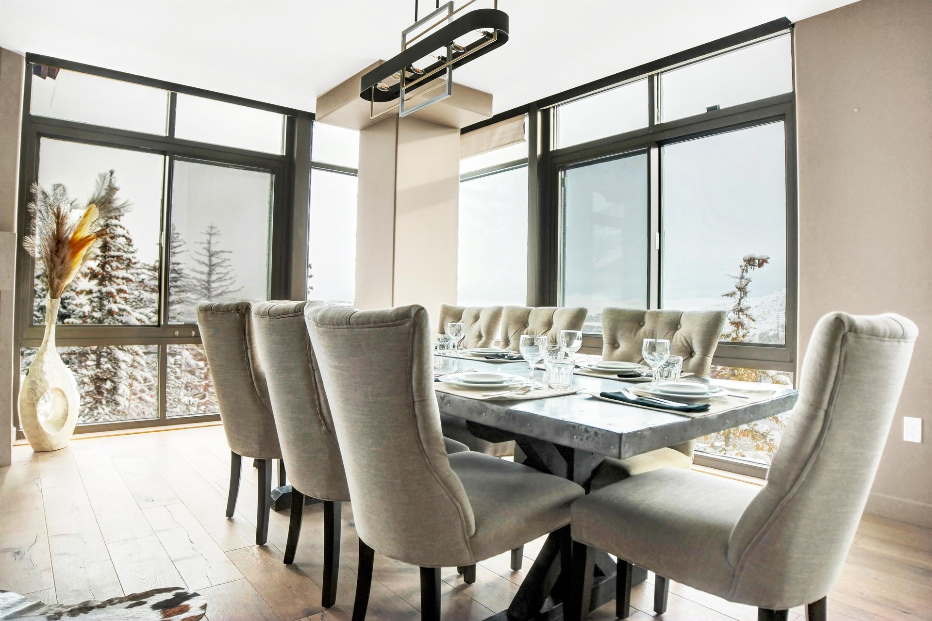 Bright dining area with seating for eight, modern chandelier and floortoceiling windows with mountain views.