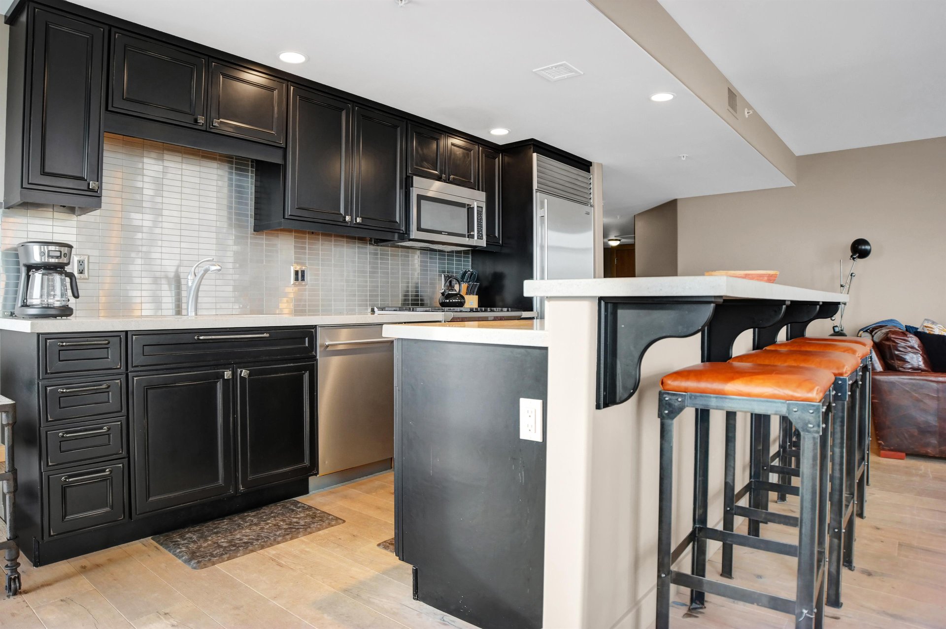 Modern kitchen with dark wood cabinetry, stainless steel appliances, stone countertops and breakfast bar seating.
