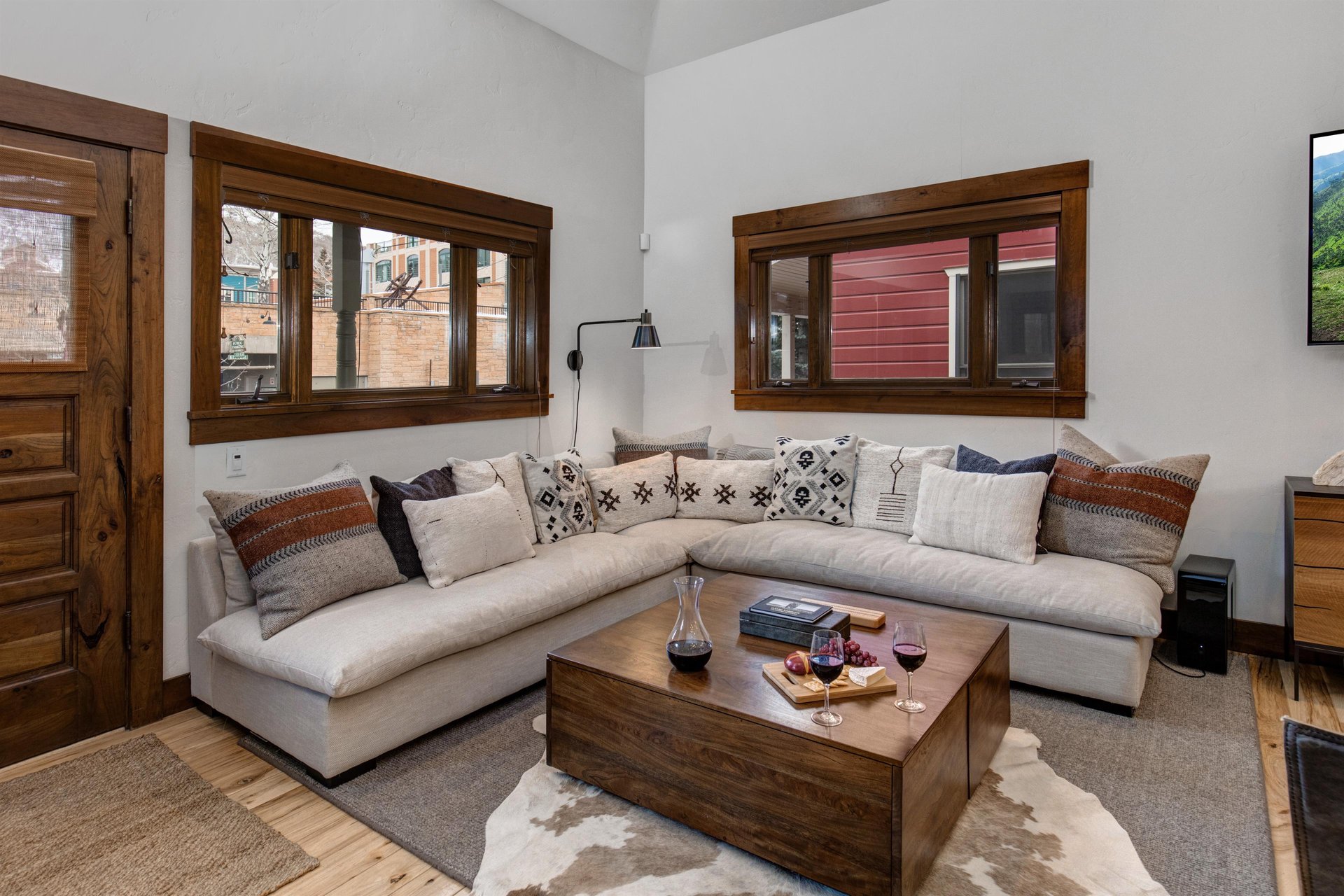 The living room featues a large sectional, wood coffee table, two leather chairs, and a wall mounted TV.