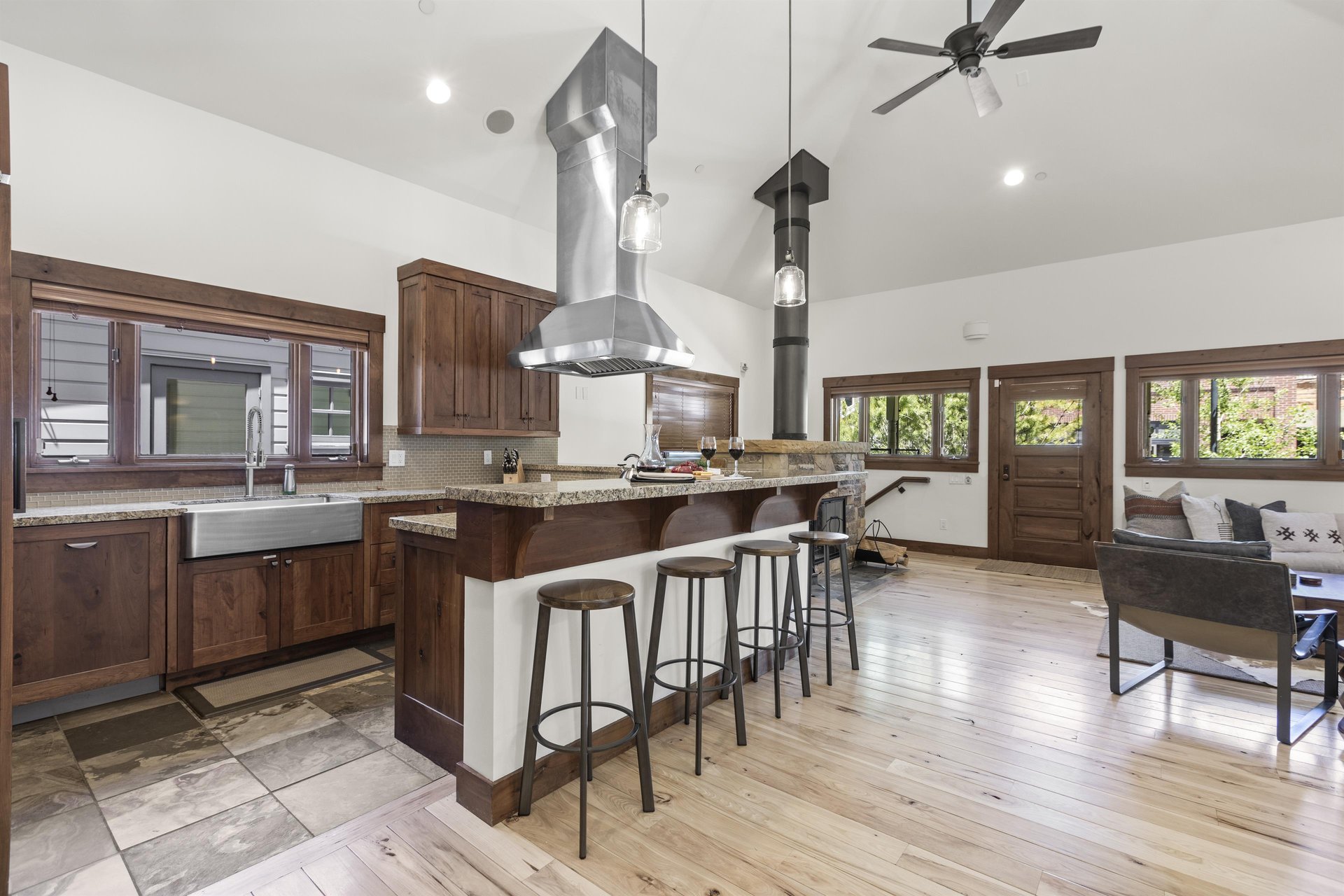 The breakfast bar with four barstools overlooks the kitchen with beautiful wood cabinets and window over the sink.