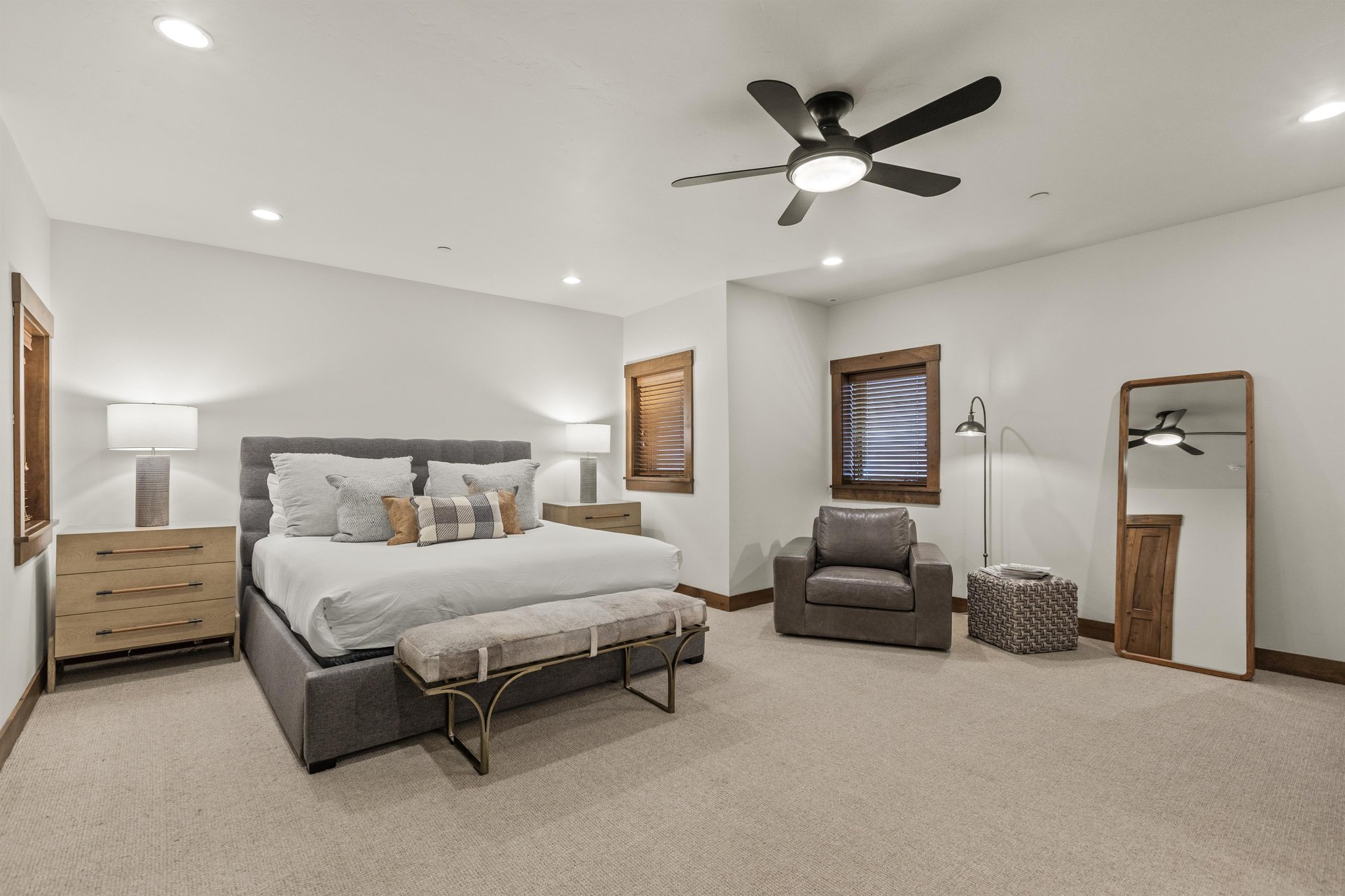 The spacious main suite has a king size bed, sitting area, ceiling fan and wooden nightstands.