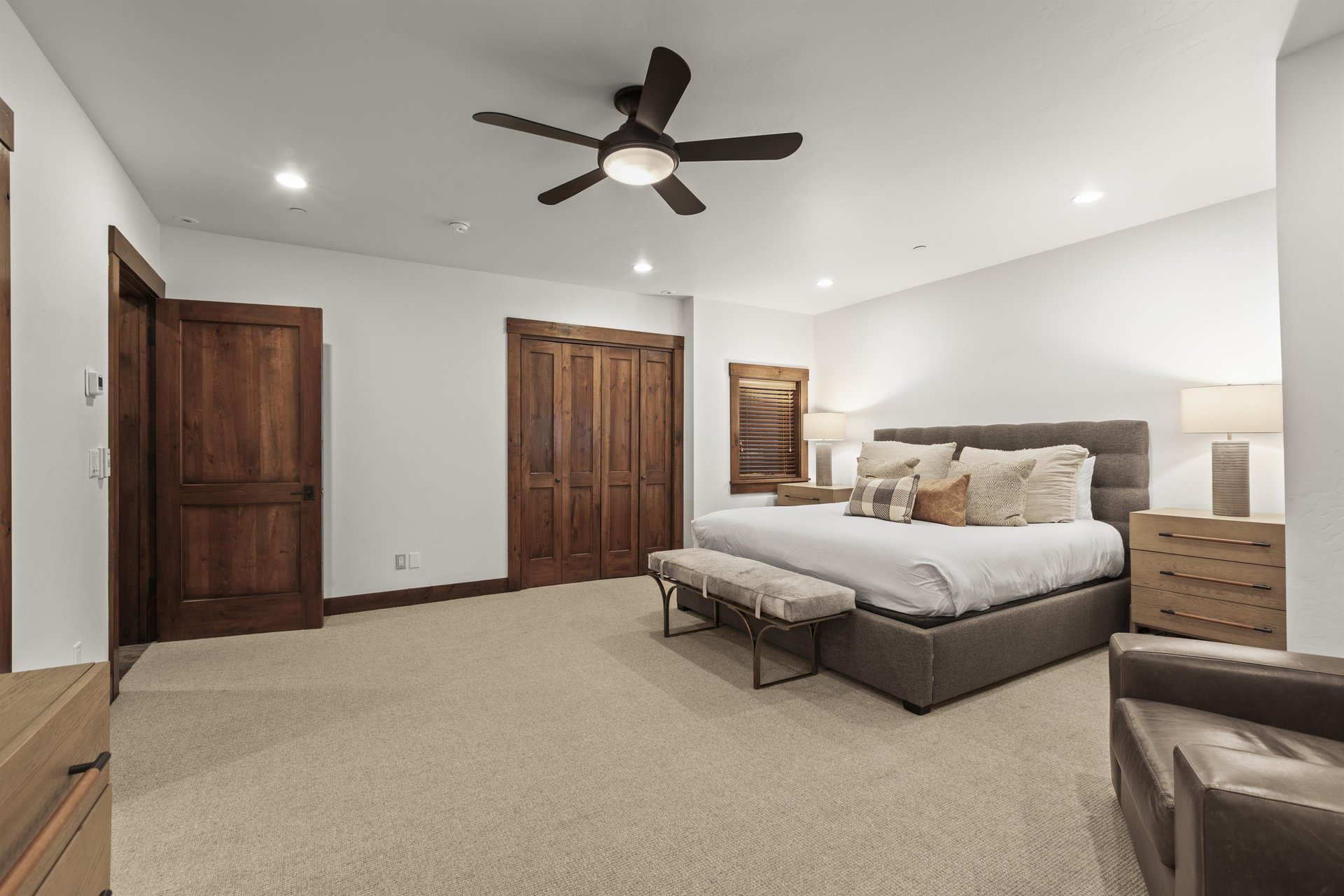 The spacious main suite has a king size bed, closet, ceiling fan and wooden nightstands.
