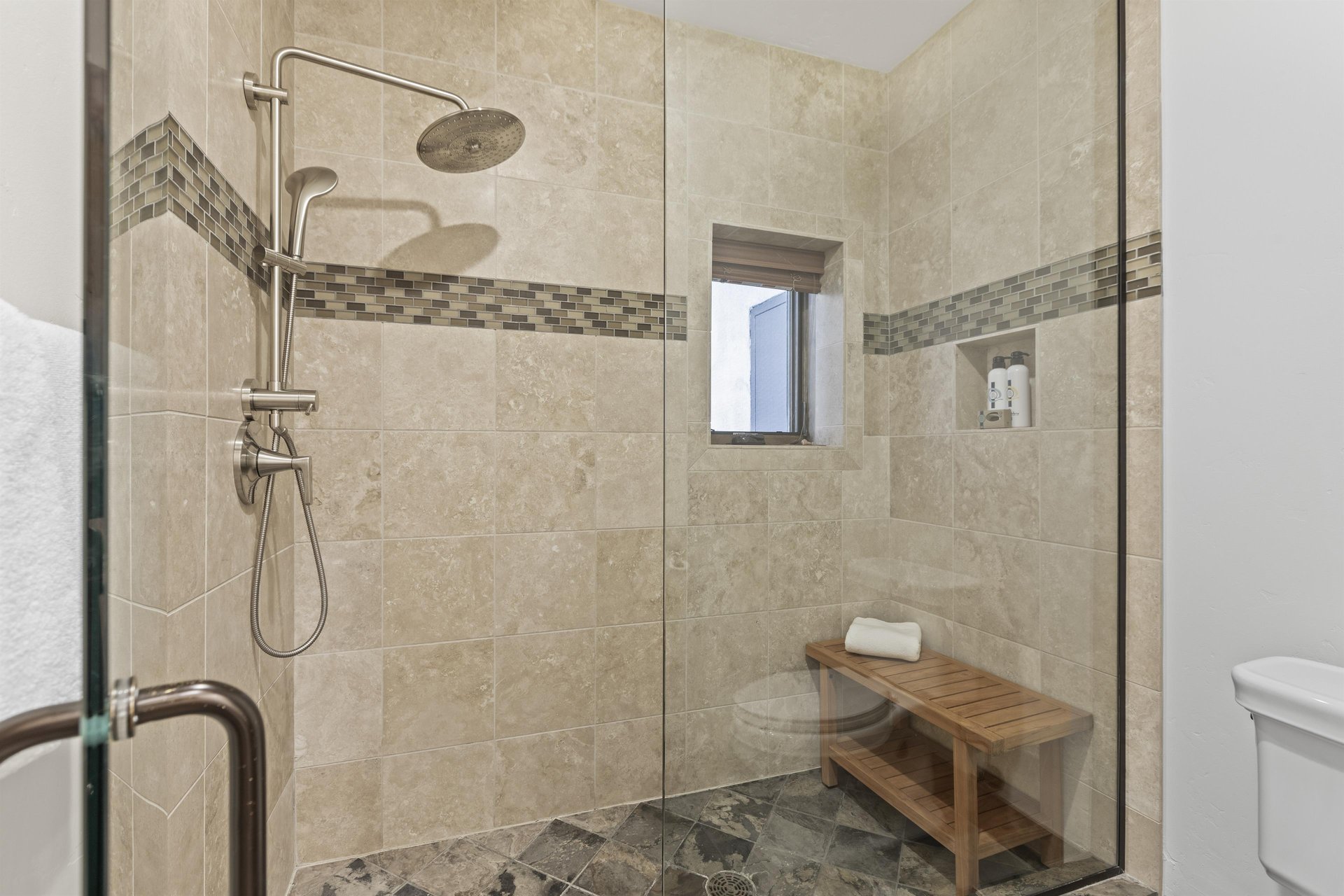 The main suite has a walk in shower with European glass door and wooden bench.