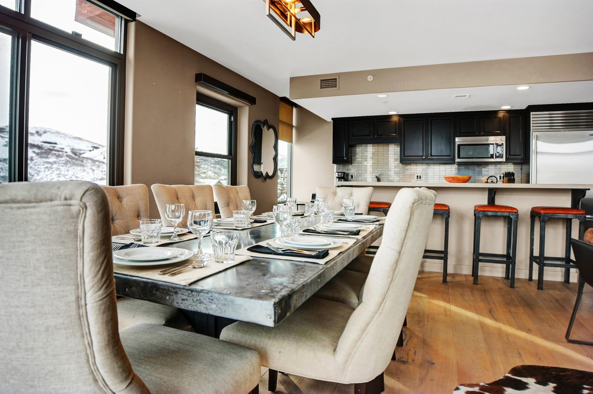 Dining area with stonetop table, upholstered seating and open views into the modern kitchen and breakfast bar.