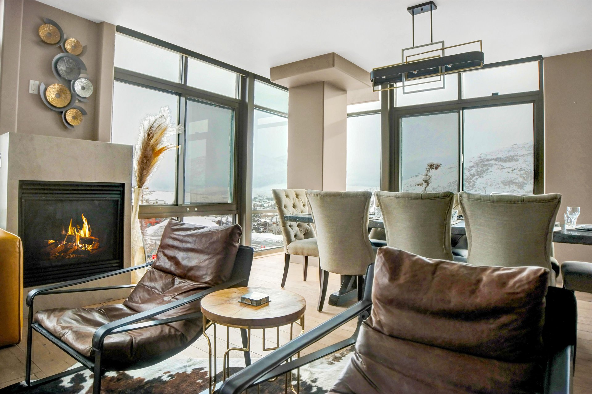 Cozy sitting area with leather chairs, modern side tables and floortoceiling windows with mountain views.