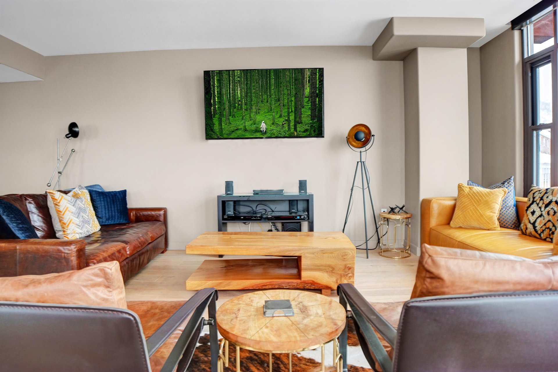 Modern living room with leather seating, wood coffee tables, wallmounted TV and contemporary mountain décor.