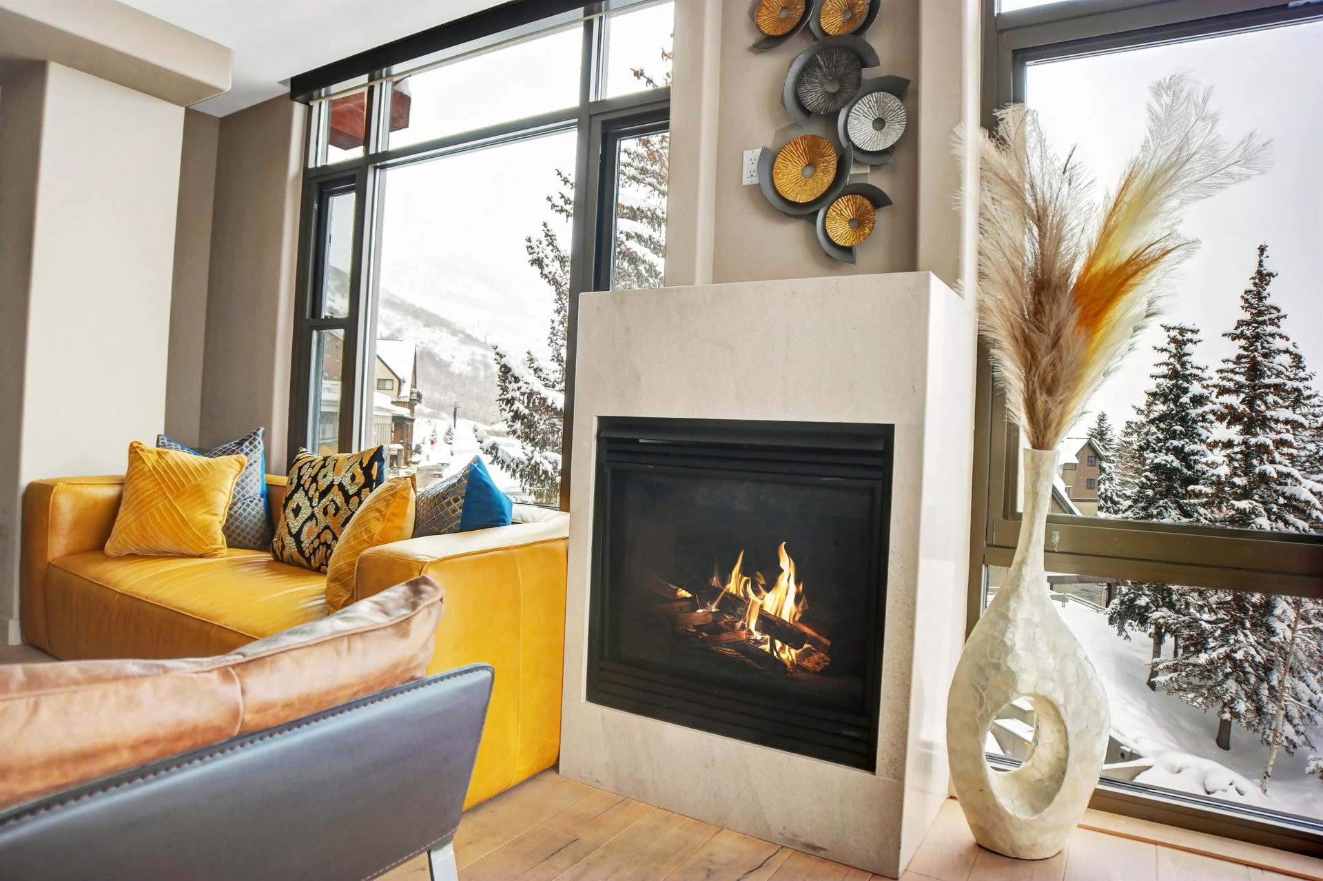 Modern gas fireplace beside floortoceiling windows with comfortable seating and views of the ski slopes.