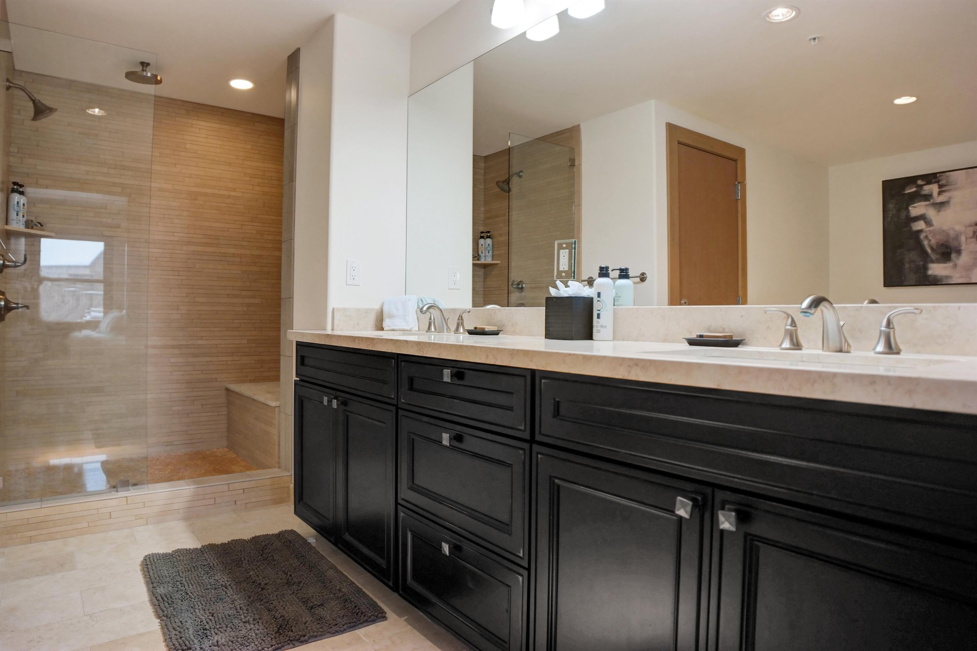 Ensuite bathroom with spacious double vanity, dark wood cabinetry, stone countertops and walkin shower.