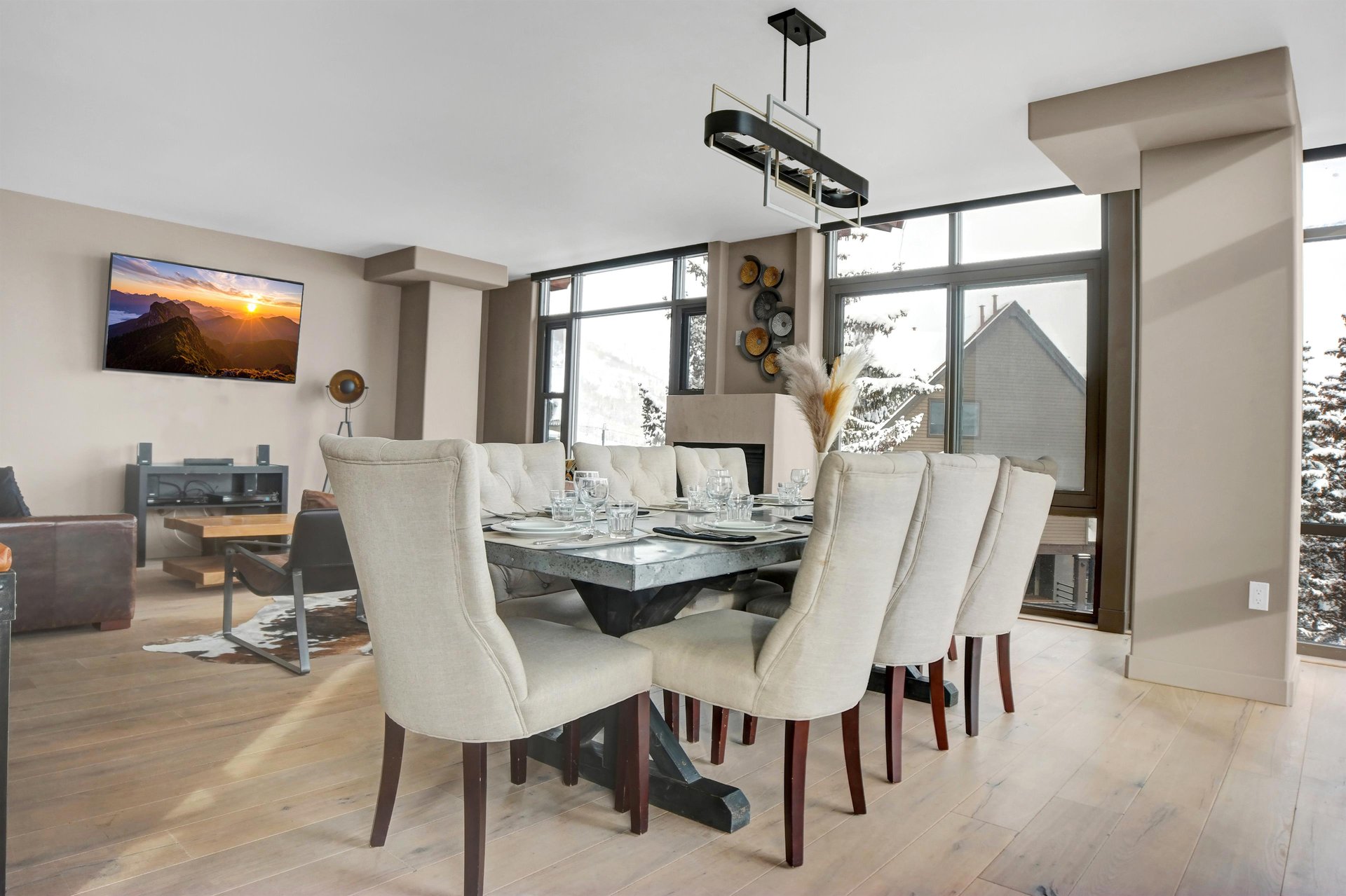 Dining table with seating for six beside large windows in the bright openconcept living area.