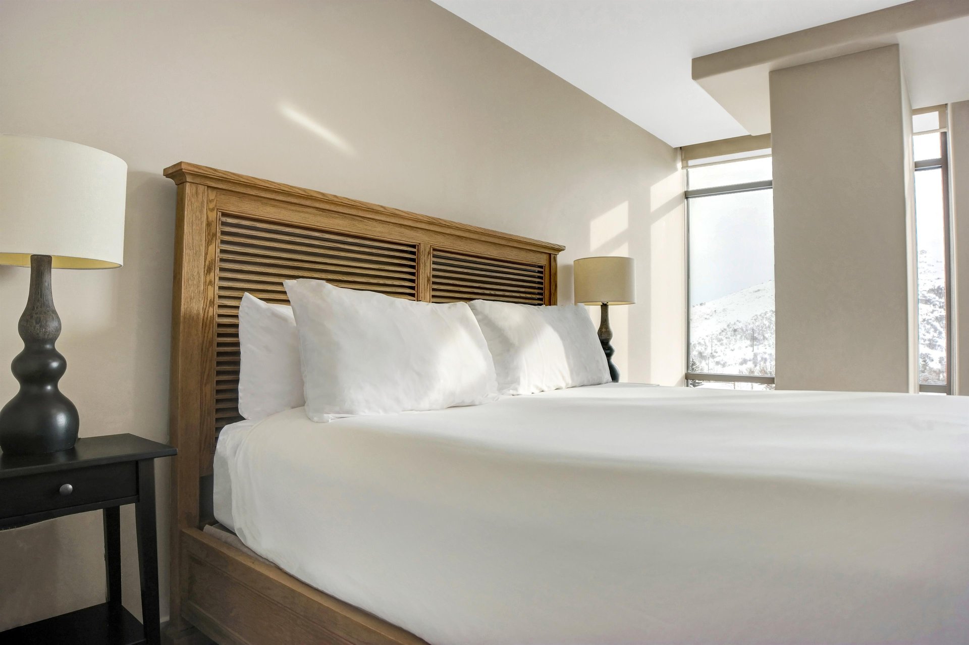 King bed with crisp white linens and a wood headboard in a bright, comfortable bedroom.