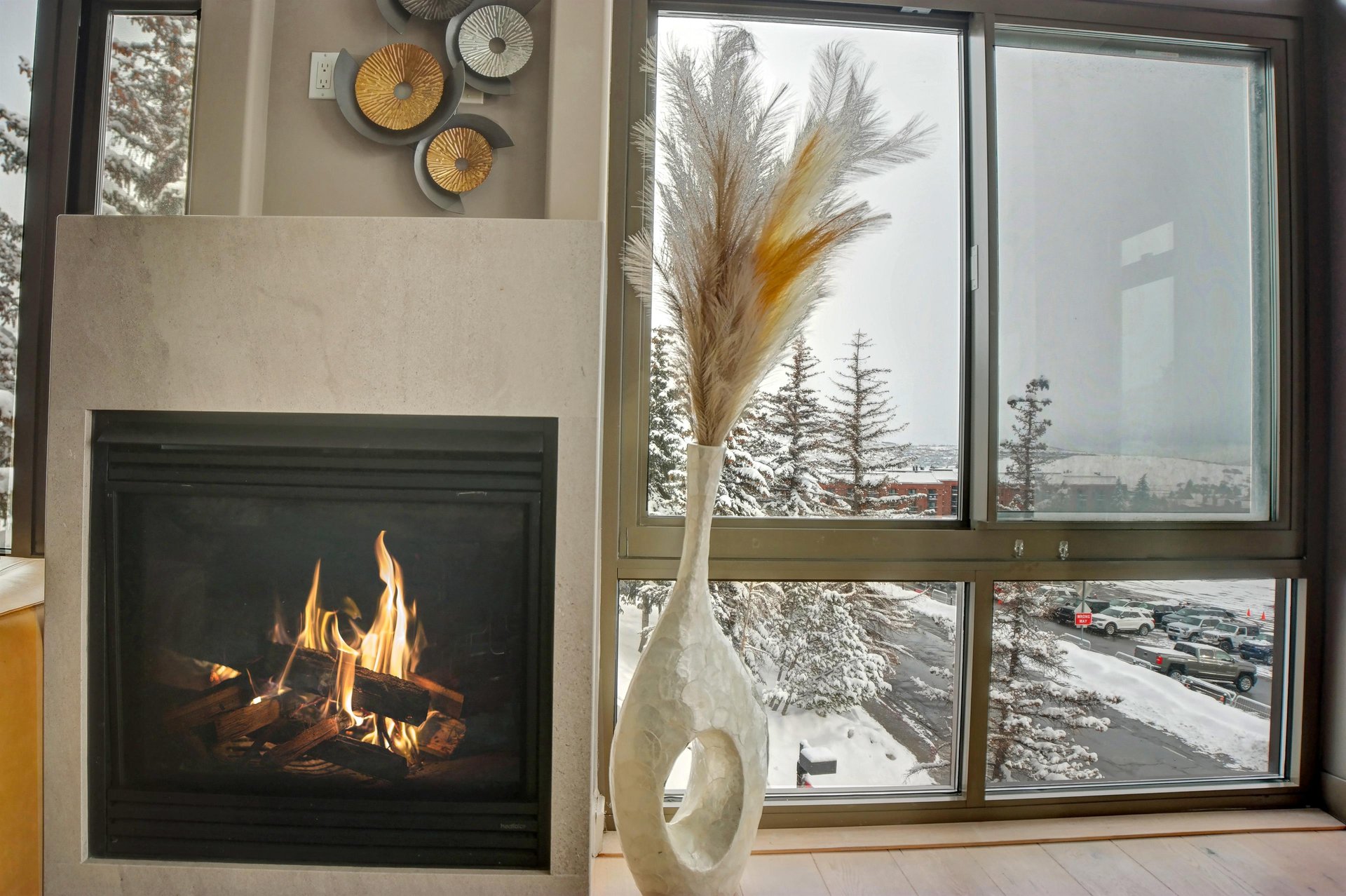 Gas fireplace beside large windows overlooking the snowy mountain surroundings.