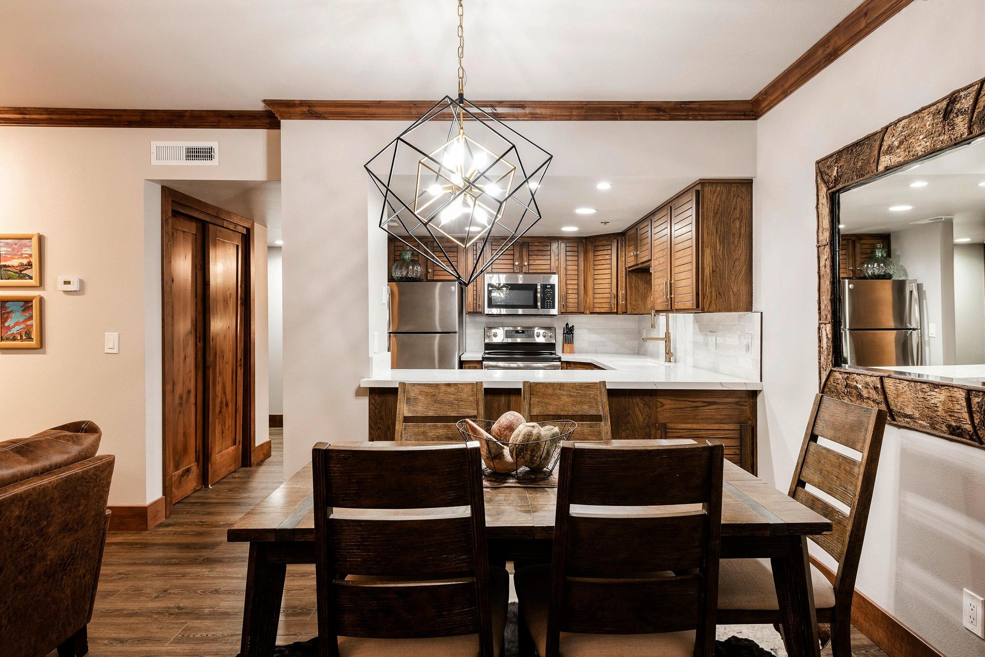 Dining area with seating for six, modern chandelier and open access to the renovated kitchen.