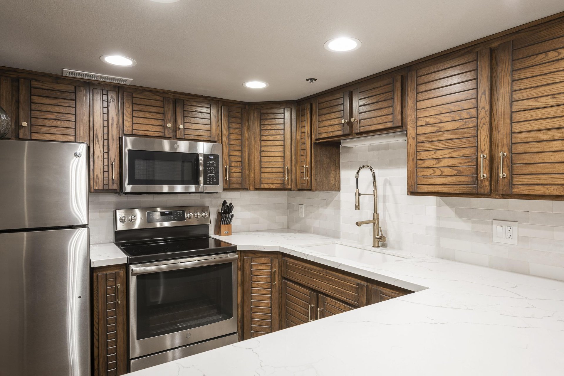 Renovated kitchen with wood cabinetry, white countertops and stainless steel appliances.