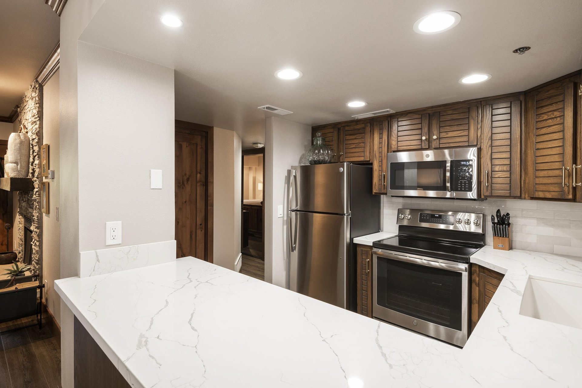 Renovated kitchen with white countertops, wood cabinetry and stainless steel appliances.
