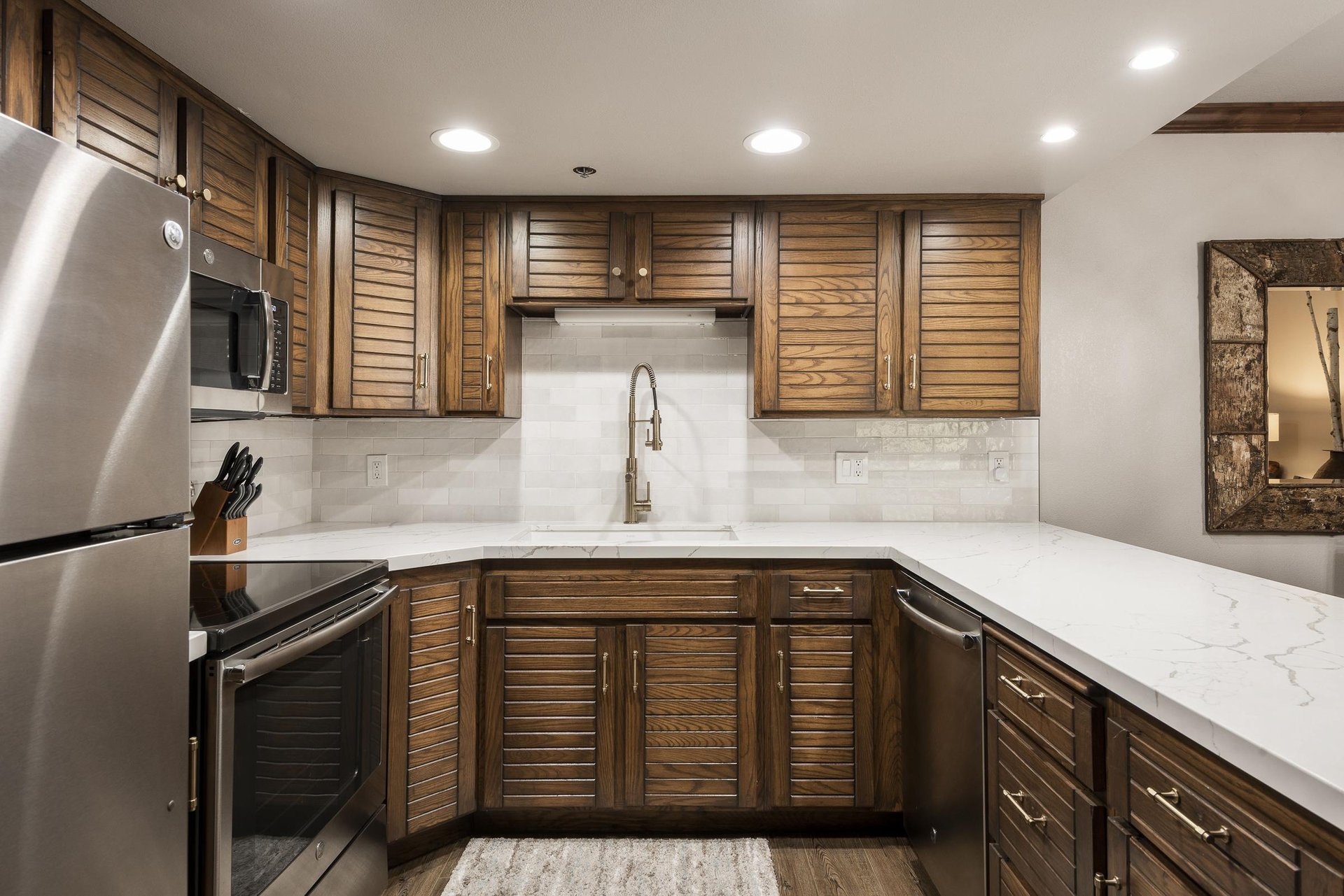 Fully equipped kitchen with wood cabinetry, white countertops, tile backsplash and stainless steel appliances.