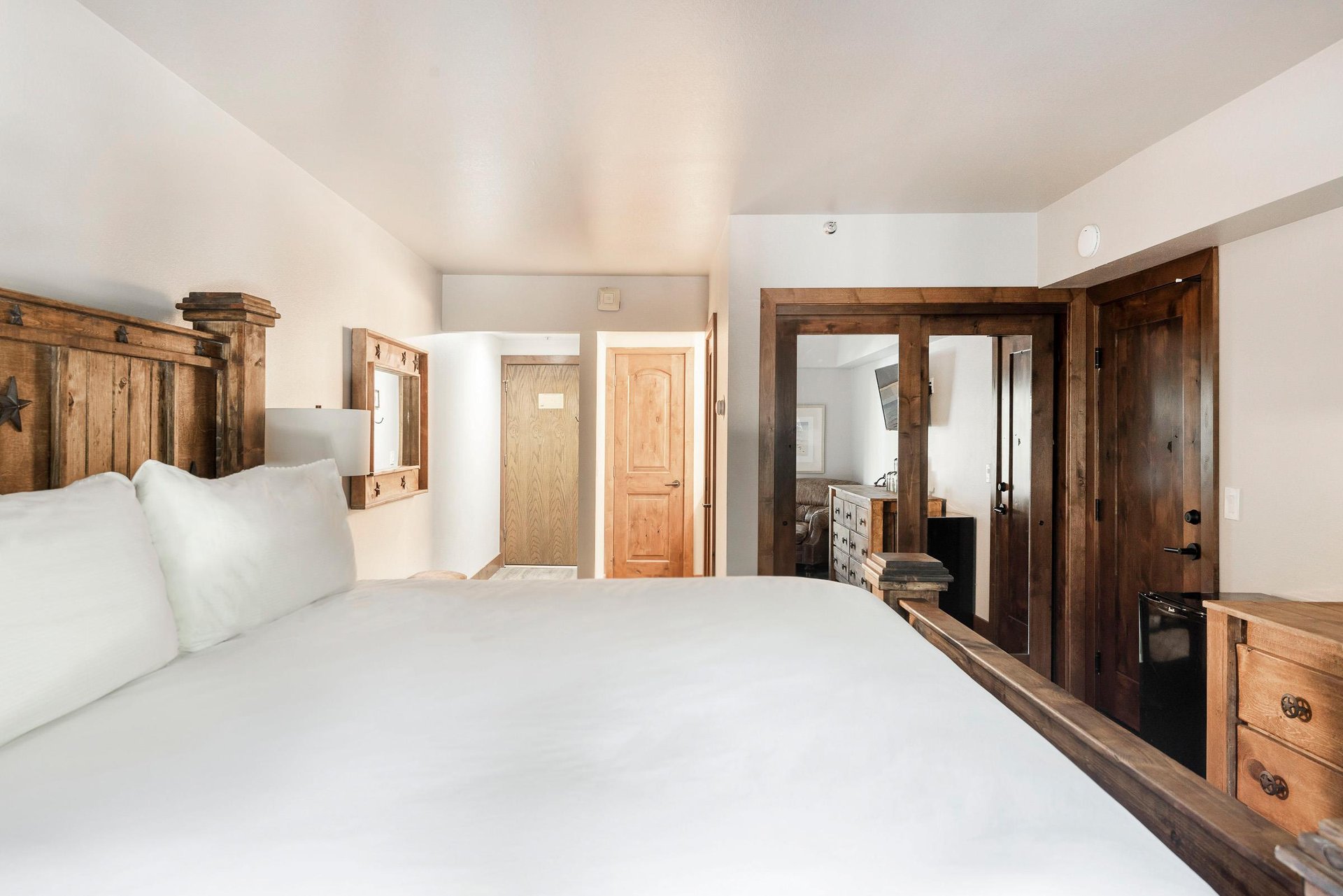 Spacious bedroom with rustic wood bed, wardrobe, dresser and warm wood accents.