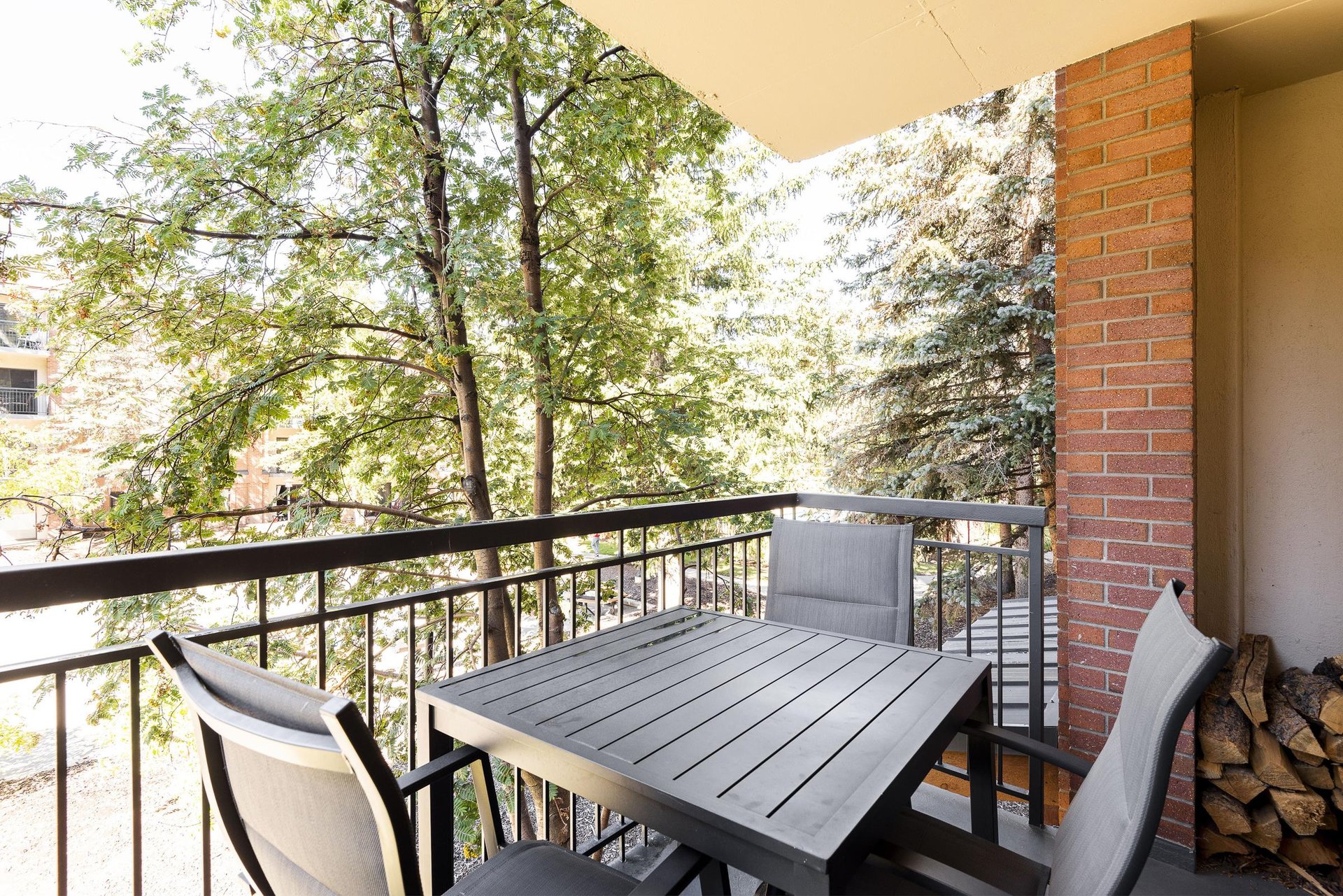 Furnished private patio with outdoor dining table and peaceful views of trees and surrounding mountains.