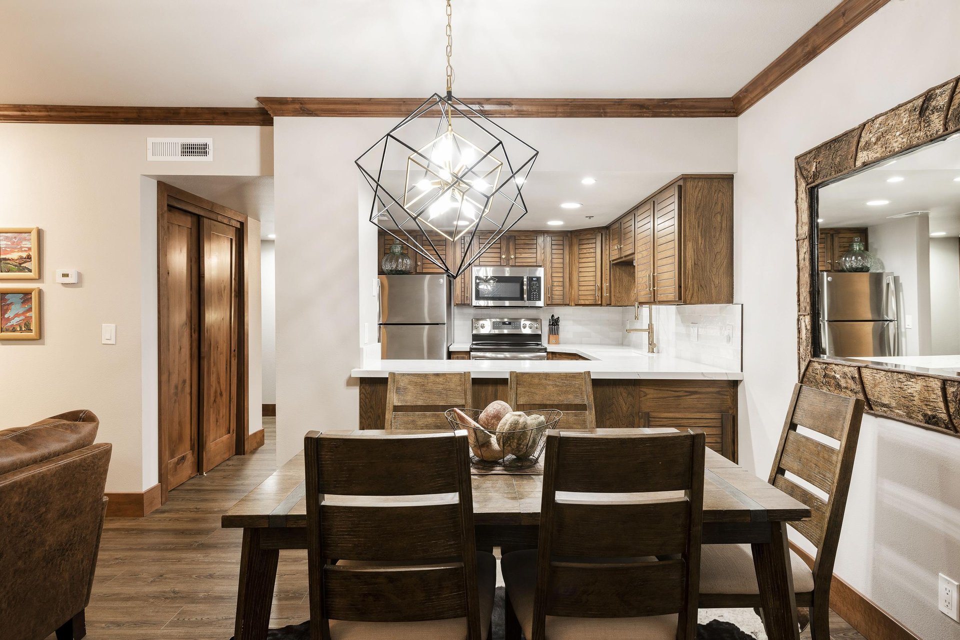 Unit 227 dining area with seating for five, statement chandelier and open kitchen in the background.