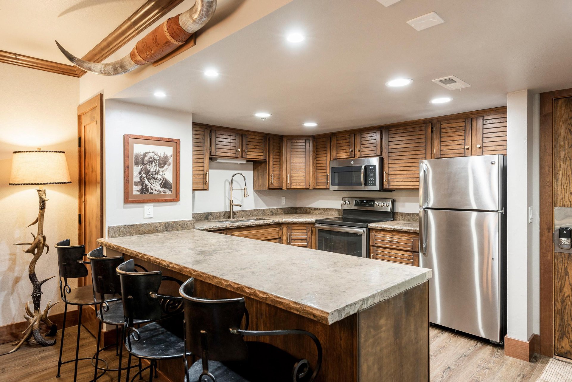 Unit 229 kitchen with granite island, bar seating, wood cabinetry and stainless steel appliances.