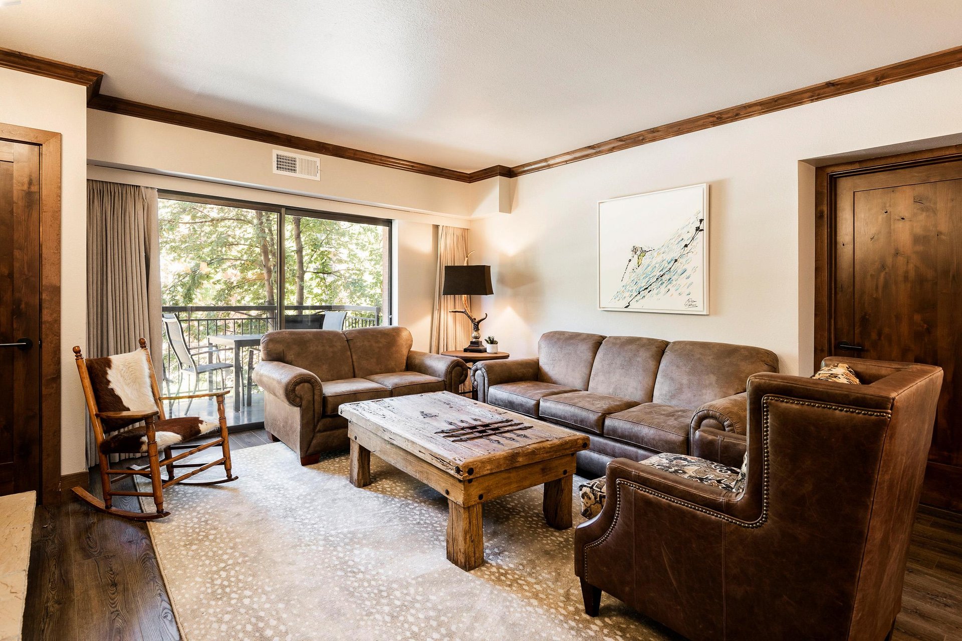 Unit 229 living room with leather seating, wood coffee table and sliding doors opening to the balcony.