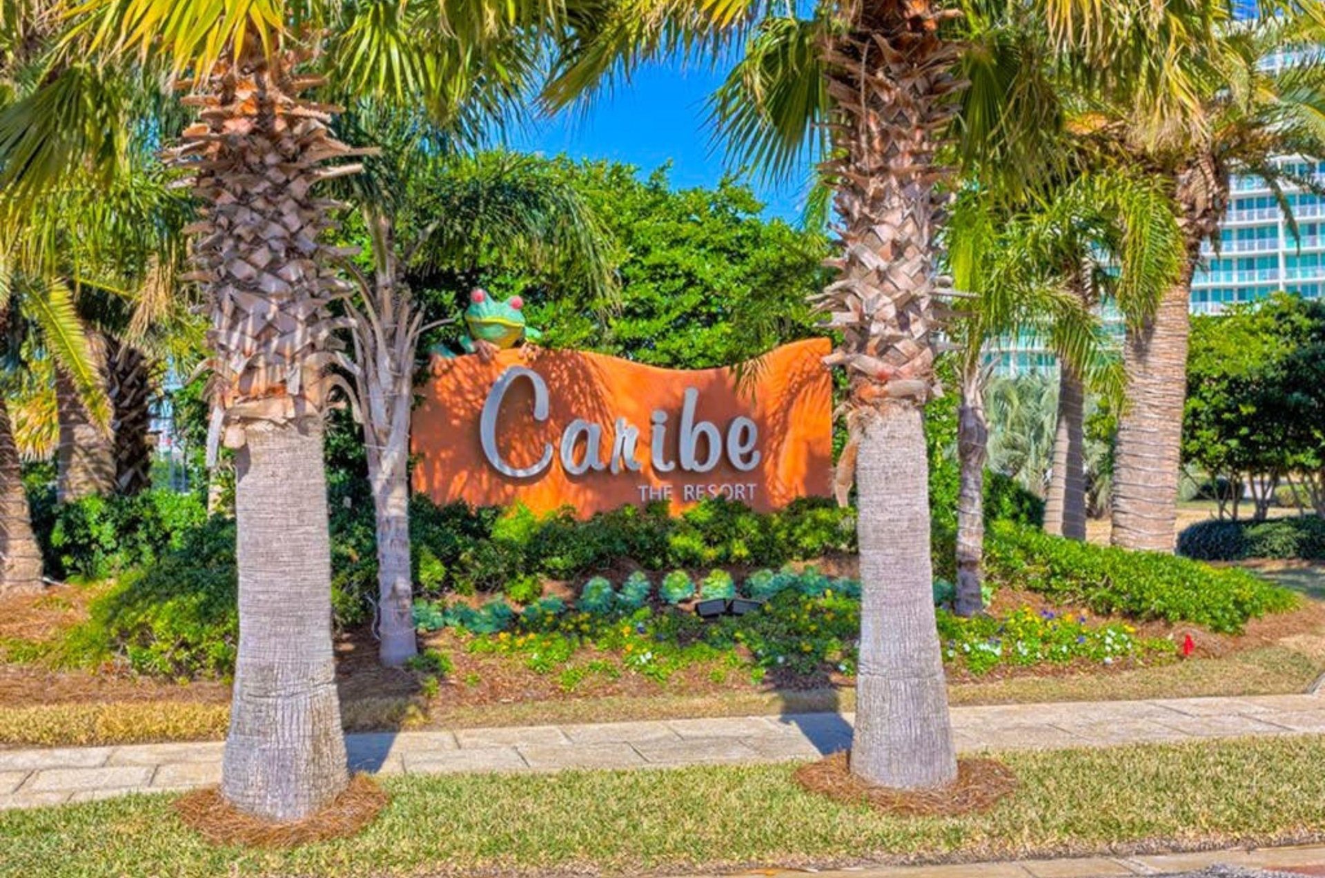 The propertys entrance sign surrounded by a tropical landscape