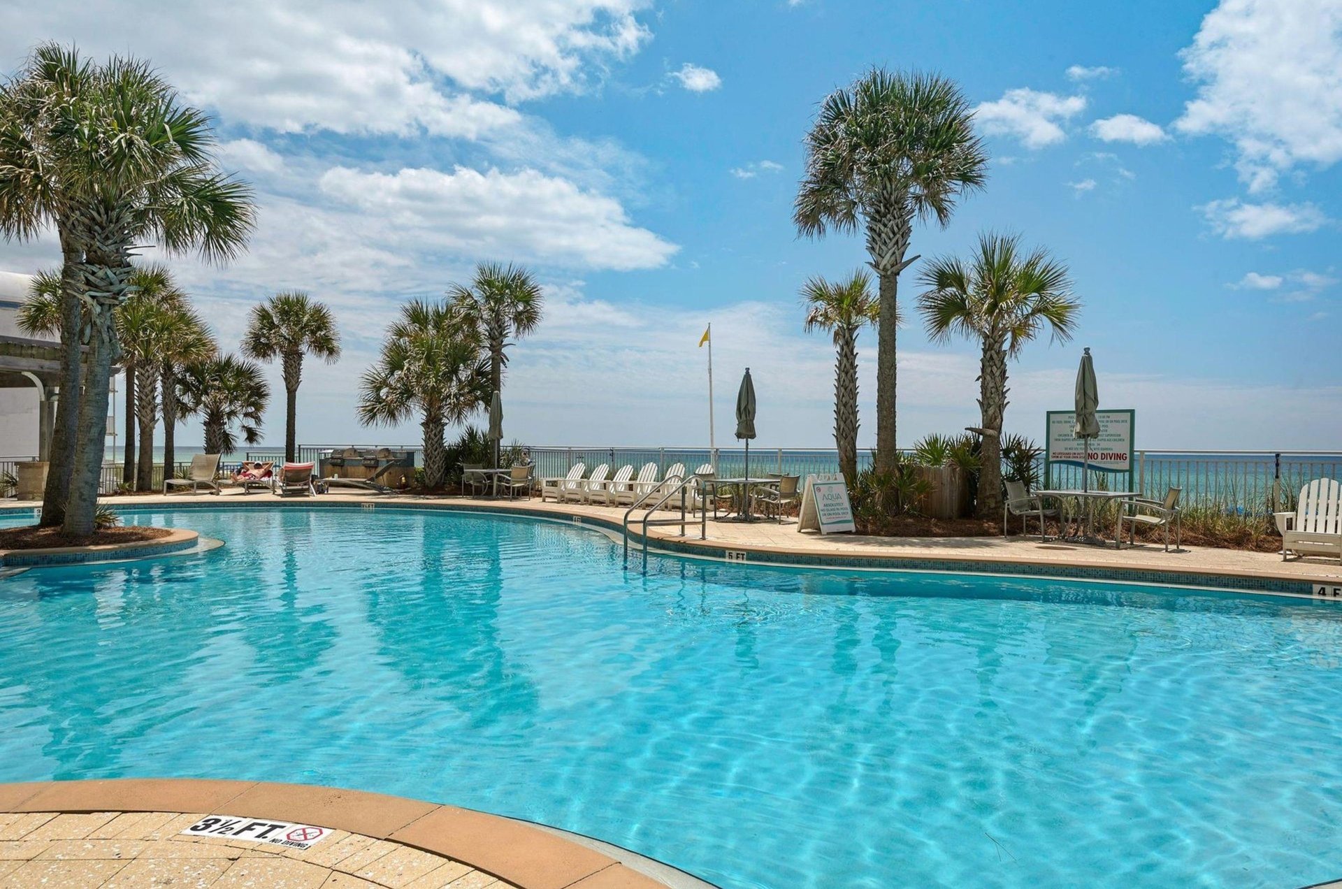 A large blue swimming pool in front of Aqua Resort in Panama City Beach Florida