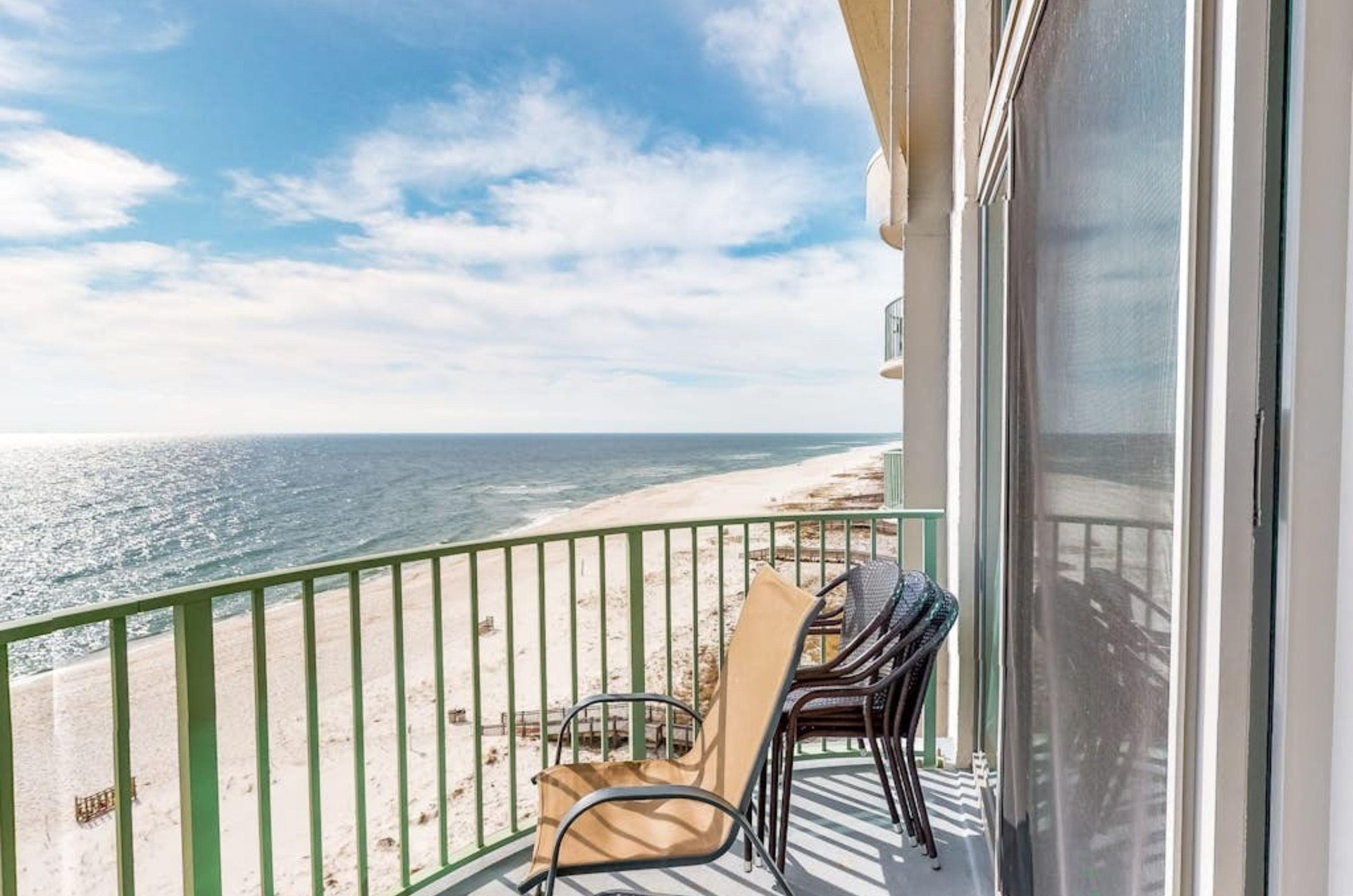 View down the coast from a private balcony with a chair and table