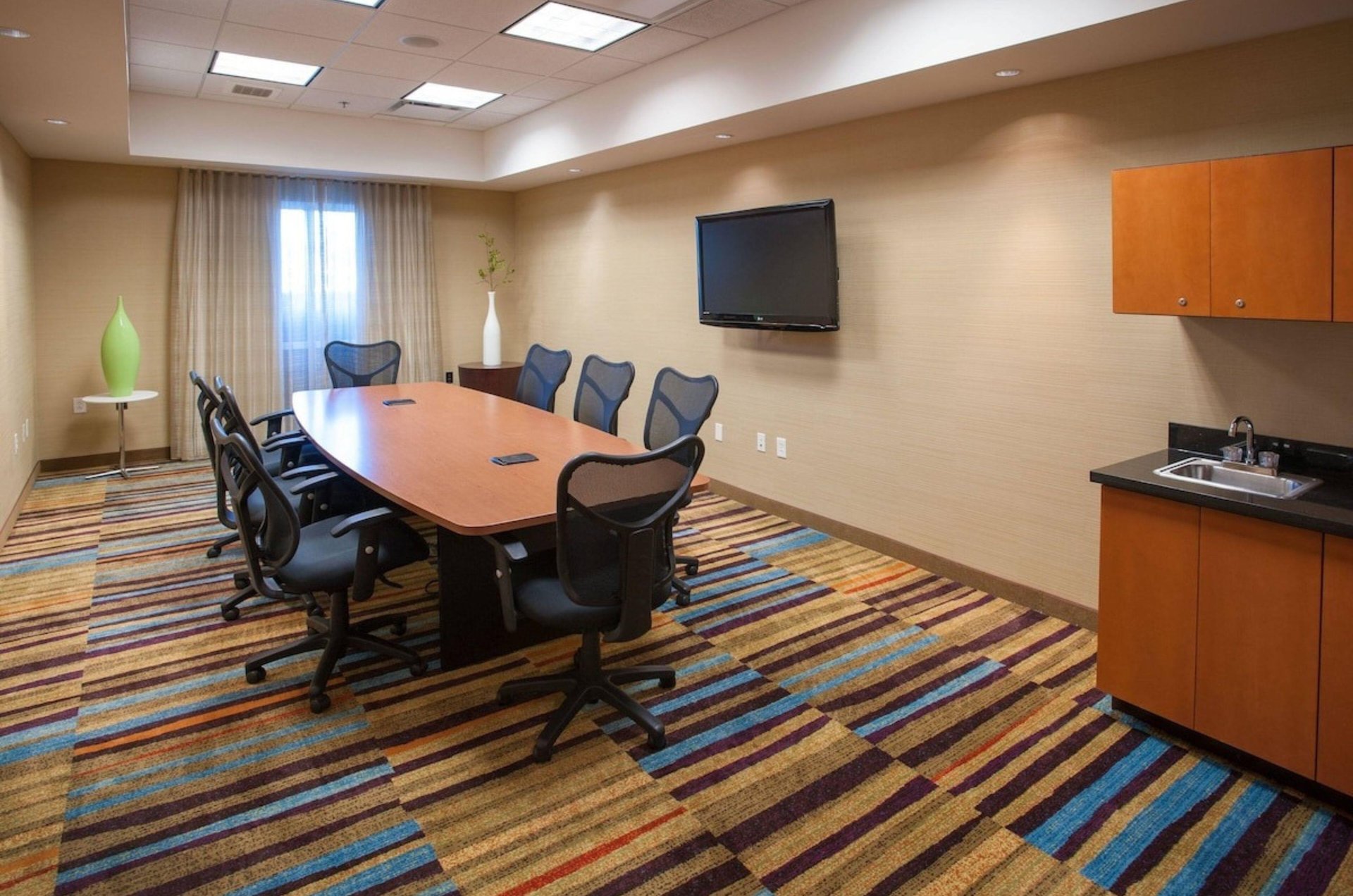 A conference table surrounded by chairs with a TV behind the table at Fairfield Inn and Suites in Orange Beach Alabama