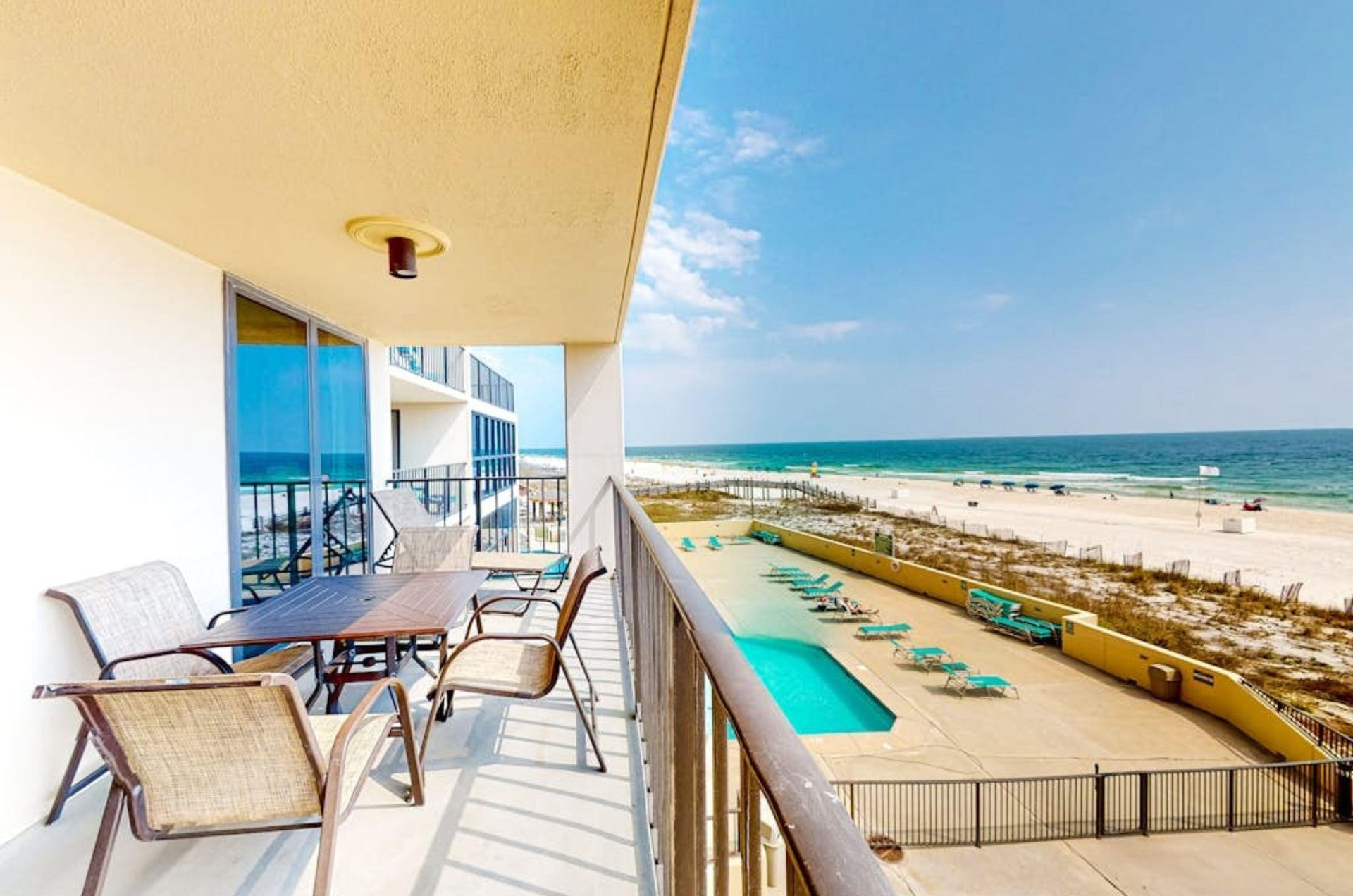 Chairs and tables on a private balcony overlooking the pool and the Gulf at Phoenix II
