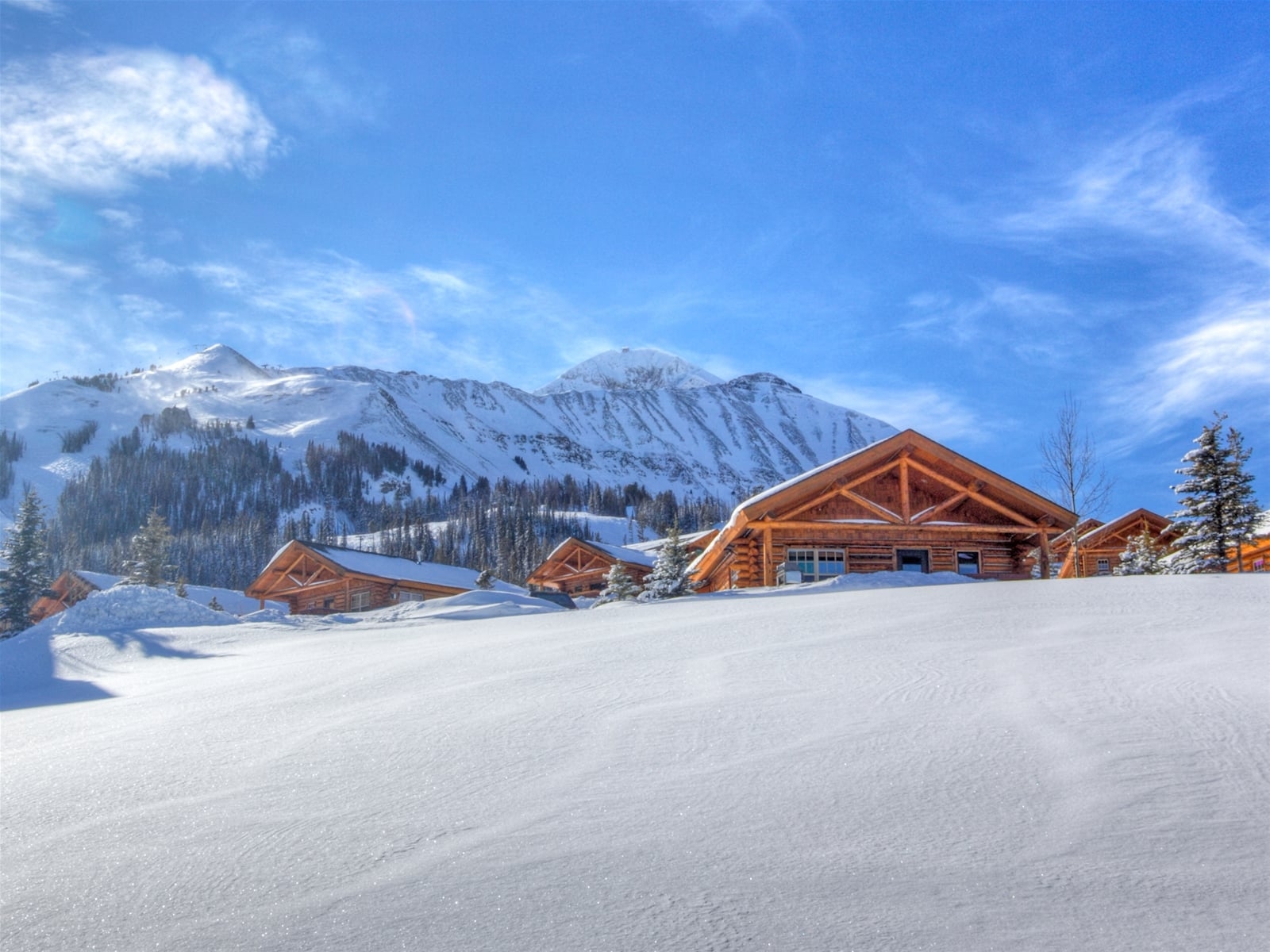 a couple of buildings in a snowy area with mountains in the background