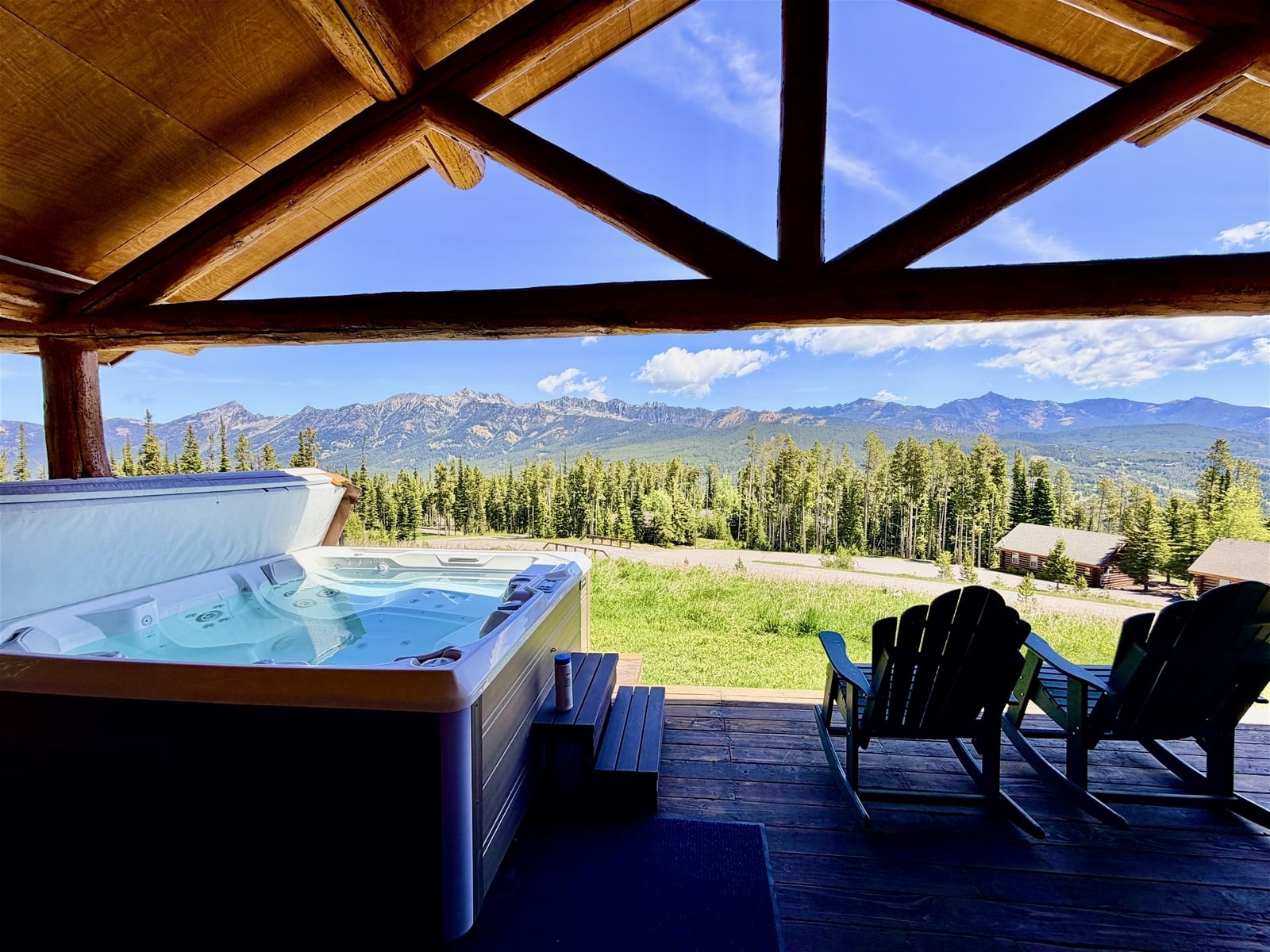 a deck with chairs and a table with a view of a mountain range