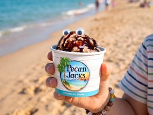 2260136 A Person Holding A Cup Of Ice Cream On A Beach