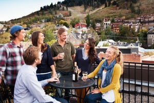 A group of friends enjoy a glass of wine on the Galleria rooftop deck with Historic Main Street and Park City Mountain in the background