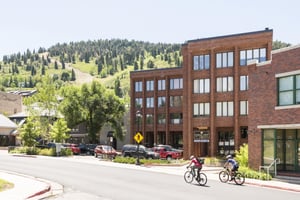 Two mountain bikers make their way up Swede Alley with Galleria in the background on a sunny summer day, green mountainside