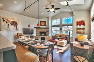 Stunning great room with vaulted ceilings, impressive window wall, open floor plan with dining room, living room, and kitchen
