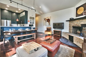 55 smart TV in the living room next to the wood burning fireplace, dining and kitchen in the background