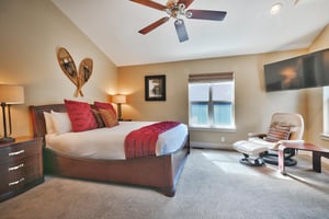 Elegant main bedroom with 48 wall mounted TV, leather accent chair and ottoman