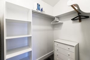 Spacious walkin closet in the main bedroom with built in cubbies, dresser, and racks