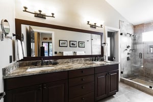 Ensuite main bathroom with granite countertops, dual vanity, glass shower door