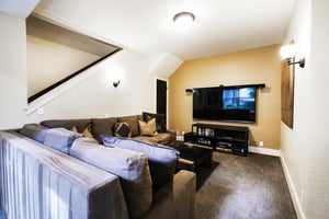 Second living room in the den with large suede sectional and 75 smart TV