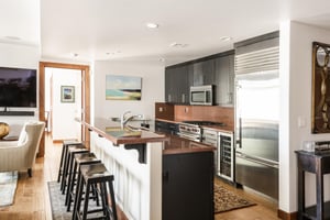 Dual tiered red granite kitchen island with wooden bar stools for 4